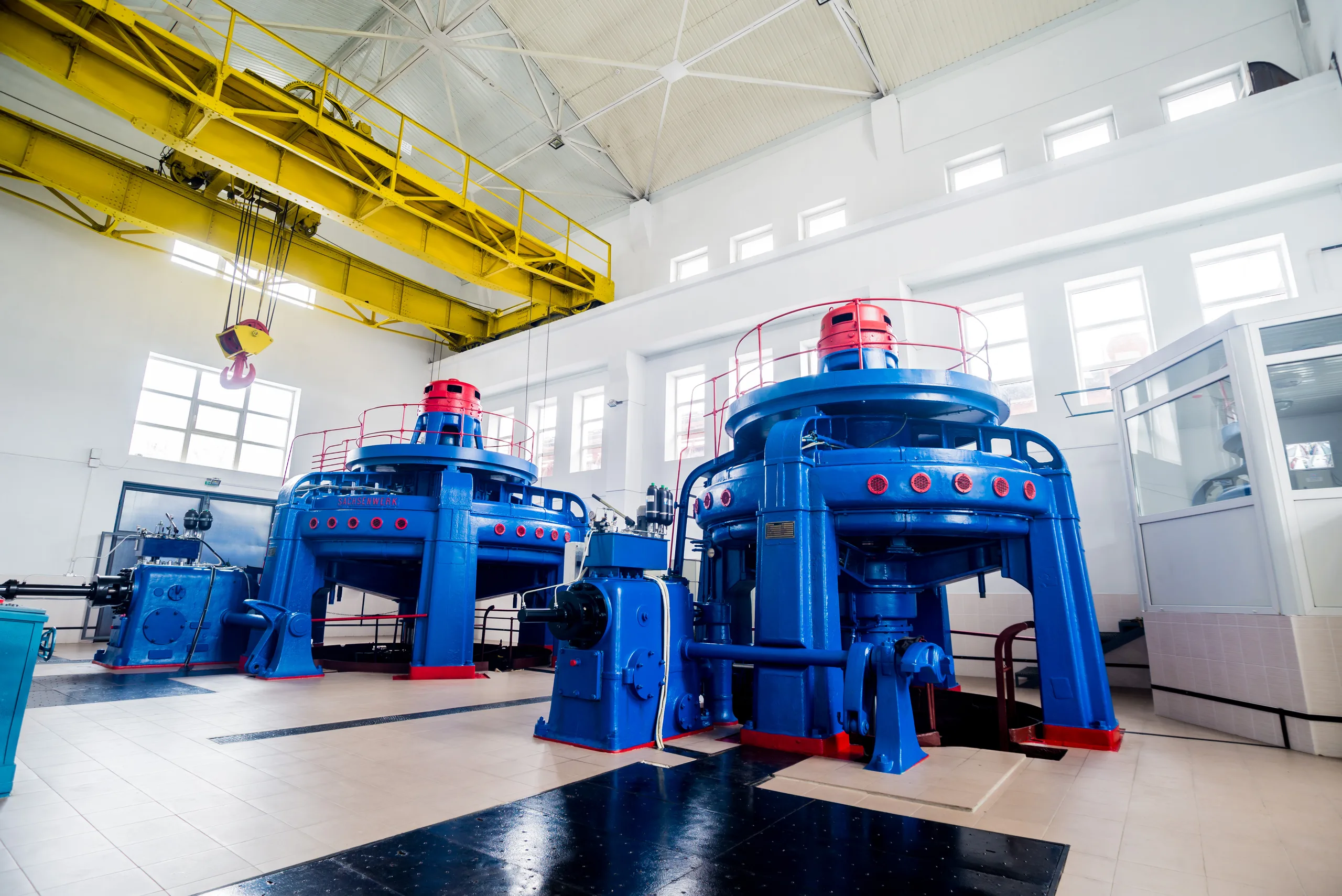 Bright machine hall at a hydroelectric power plant with two generators and an overhead crane